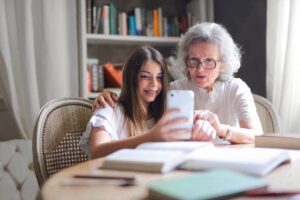 Grandmother and granddaughter looking at a smartphone together at a table.