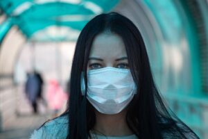 Woman with blue eyes wearing a face mask in an enclosed walkway. 5 Reasons To Wear Masks.