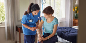 Home health care nurse attending to a patient receiving IV therapy.
