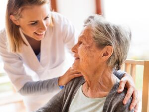 Caregiver smiling and assisting elderly woman.