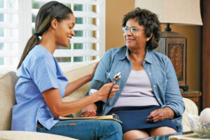 Nurse taking senior woman's blood pressure during a modern house call.