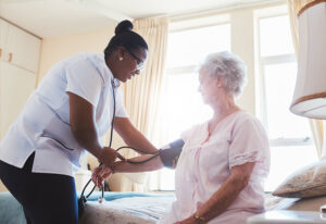 Home health: Nurse taking blood pressure of elderly woman in her bedroom.