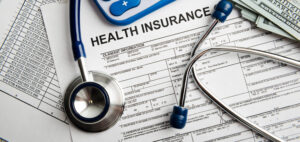 Health insurance form with stethoscope, calculator, and money. Text: "Health Insurance".