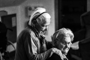 Two elderly women embracing, one with a headband, showcasing the compassion of home health care.