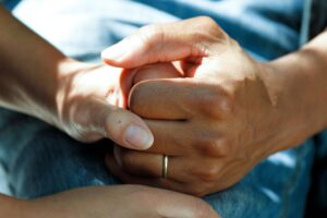 Close-up of hands clasped together, symbolizing support in hospice care.