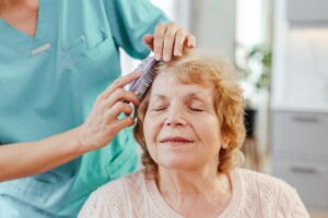 CNA brushing patients hair with a hairbrush while patients sits down and enjoys 