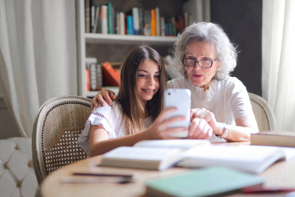 Grandmother and granddaughter looking at a smartphone together at a table.