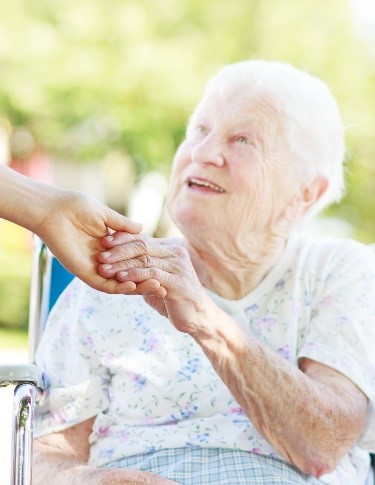 Elderly woman in wheelchair receiving assistance.