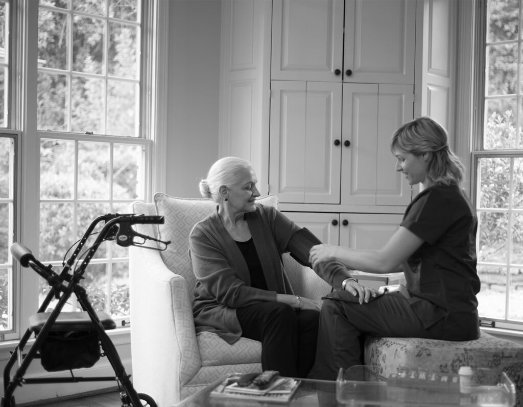 Home health aide assisting senior woman in her home. Walker nearby.