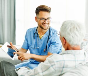 Home health care worker showing tablet to senior man. Avatar Home Health Services.