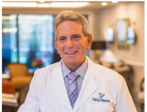 Dr. Charles Vialotti in a white coat with the Holy Name logo, smiling for the camera.