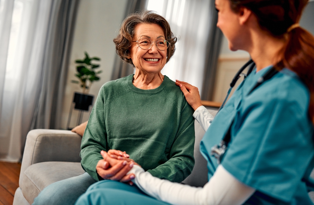 Home Health or Hospice patient being visited by a nurse in their own home, holding hands and being comforted.